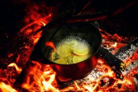 Bild: Glühwein-Topf mit Orangenschalen über glühendem Feuer